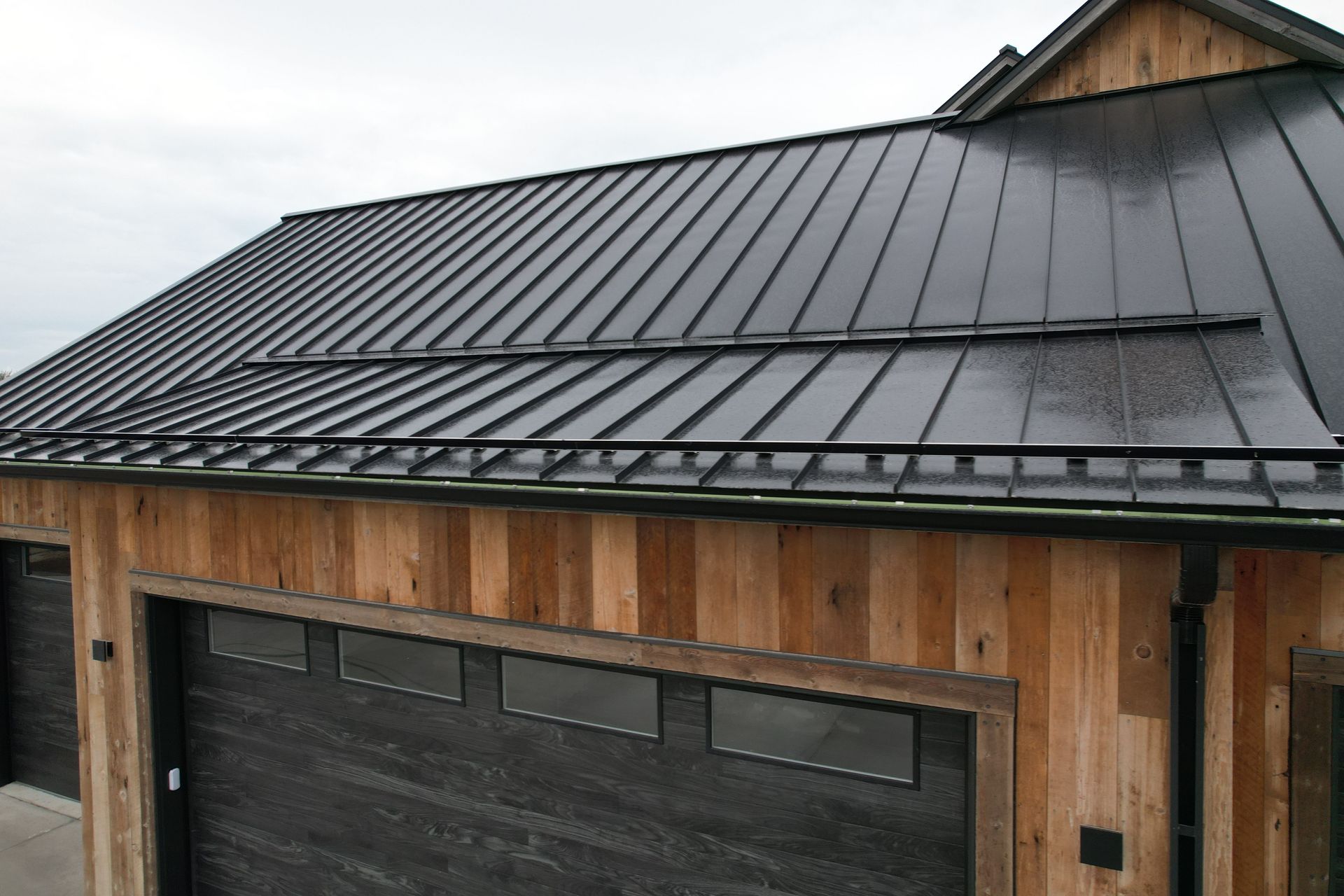 A house with a black metal roof and wooden siding.