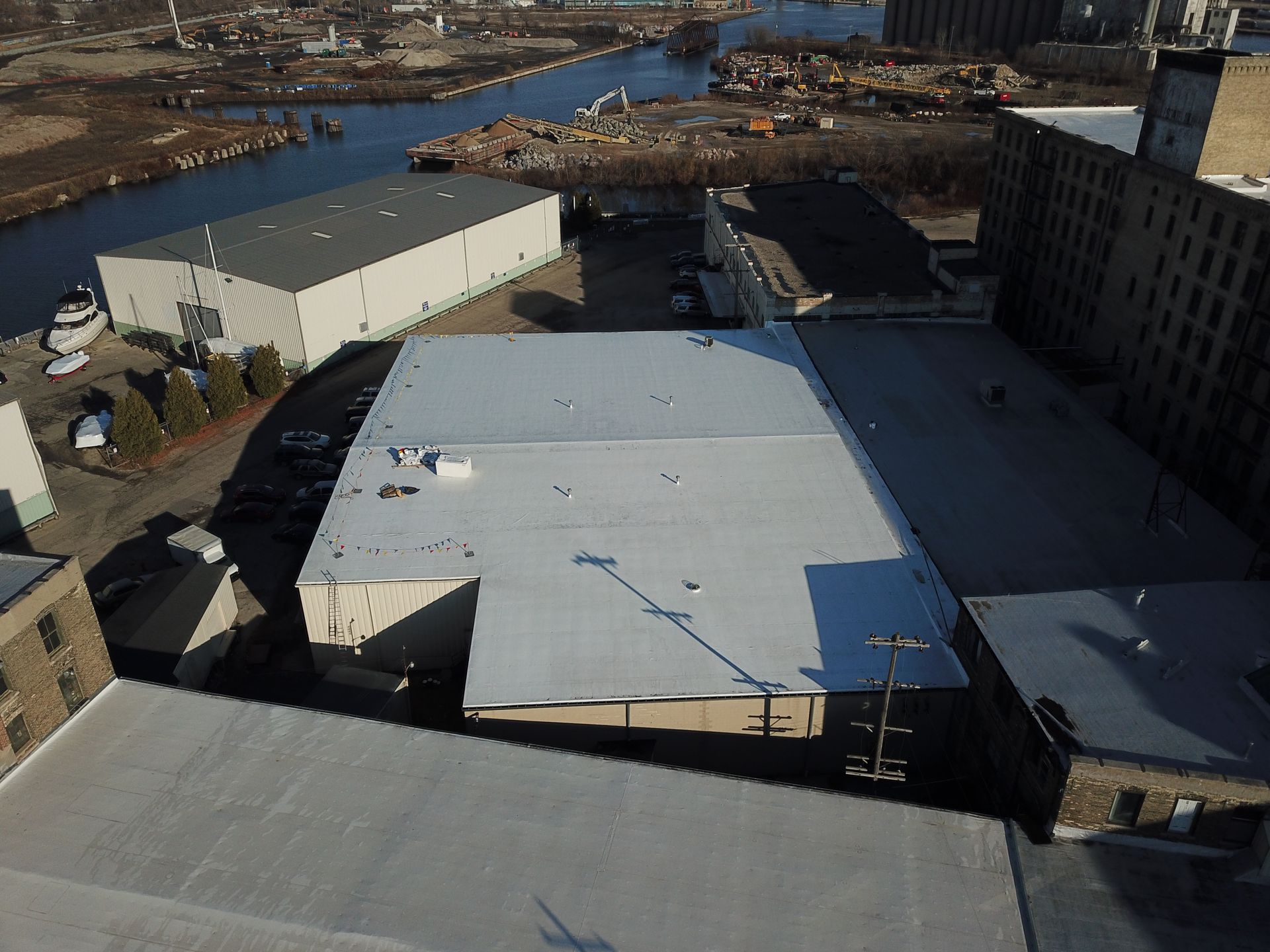 An aerial view of a building with a white roof and a river in the background.