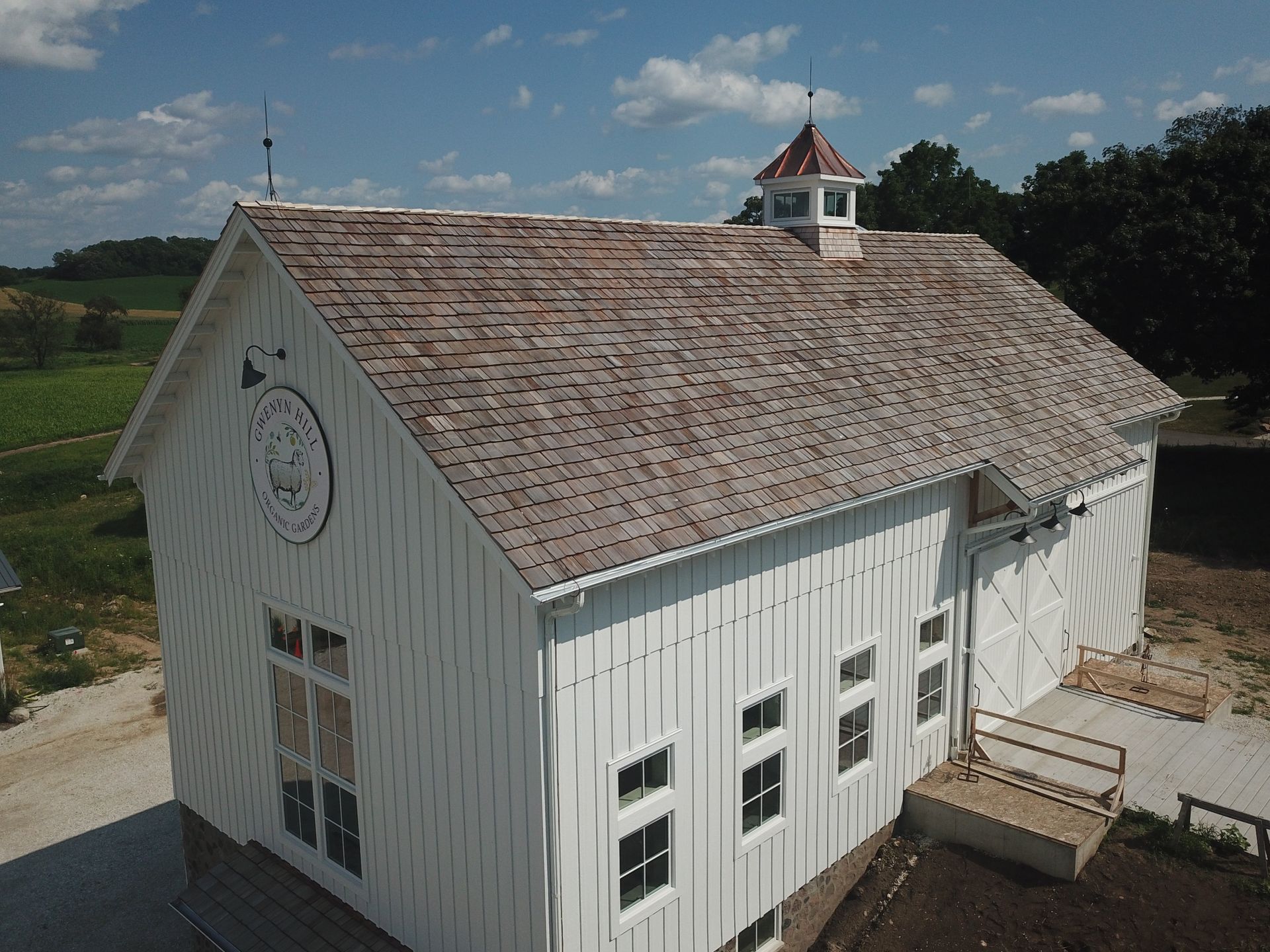 An aerial view of a white barn with a brown roof.