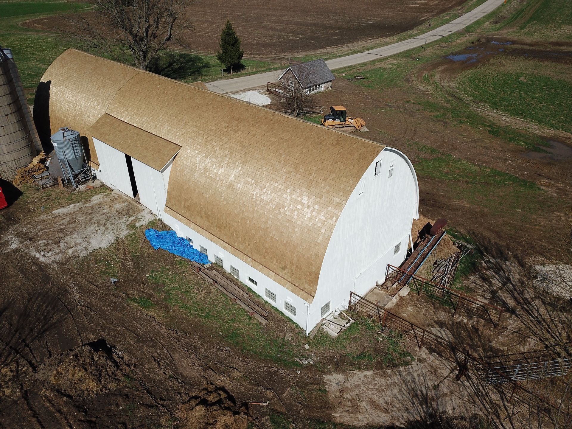 An aerial view of a large white barn with a thatched roof.
