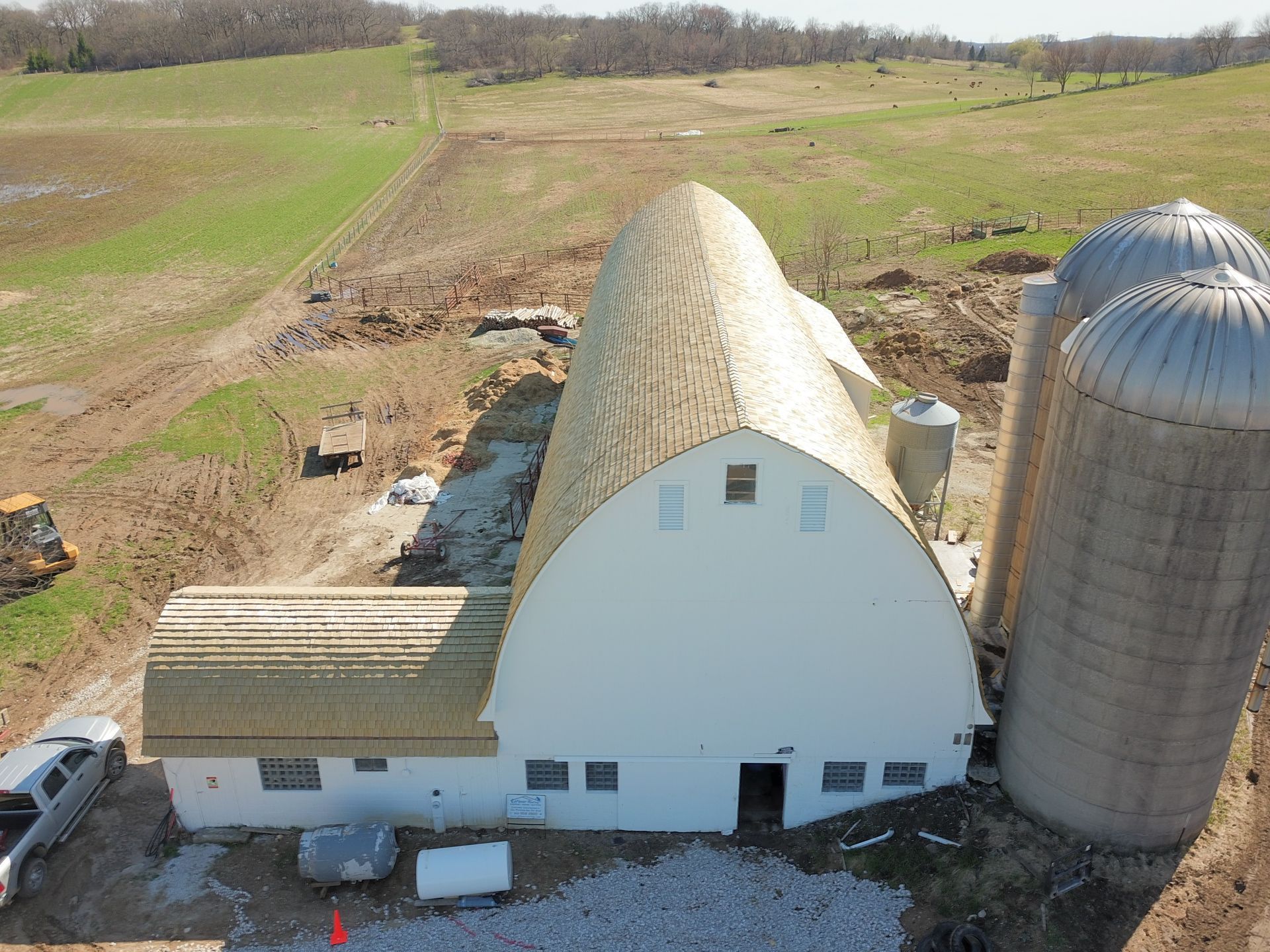 An aerial view of a barn and silos in a field.
