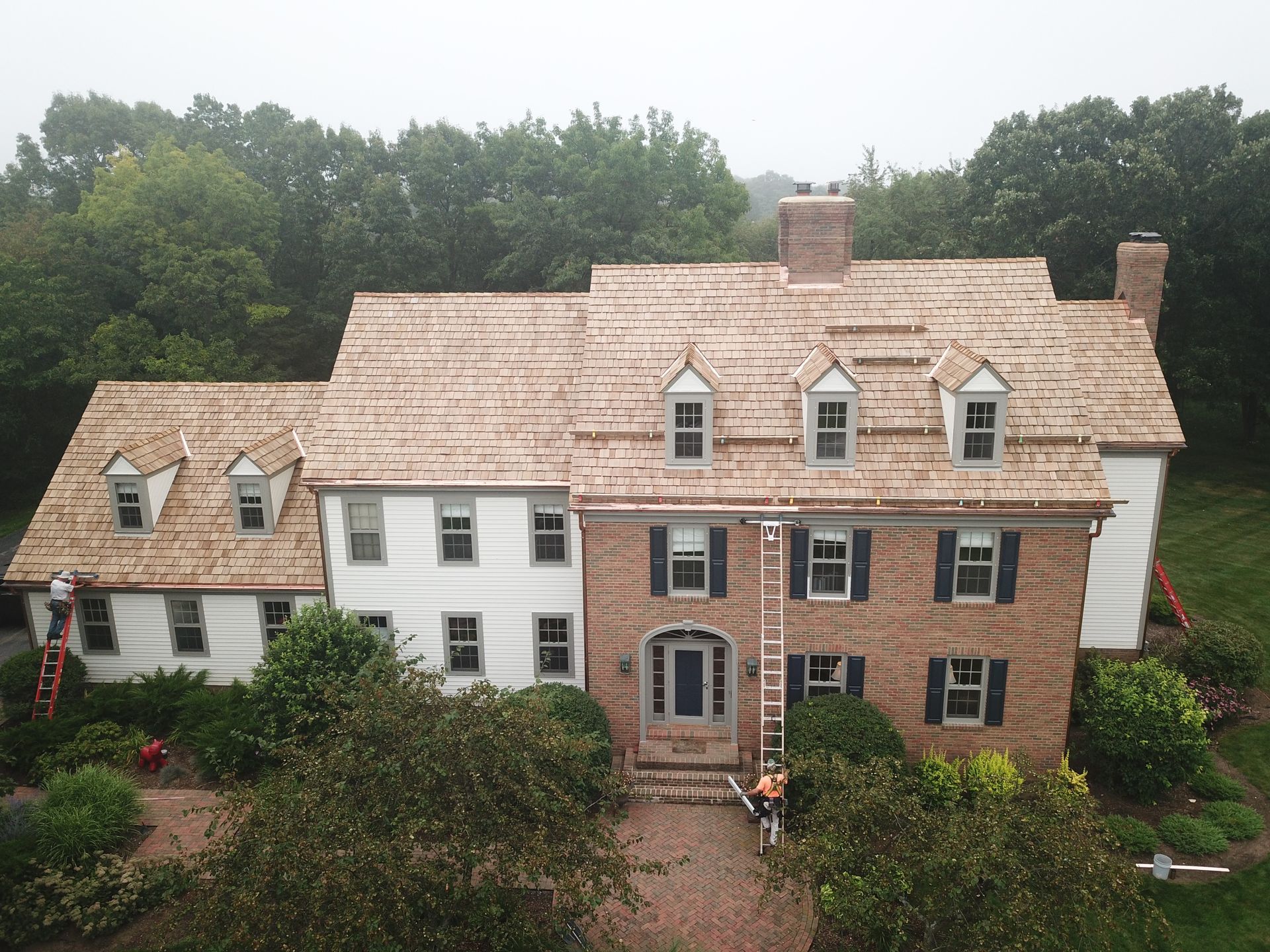 An aerial view of a large brick house with a wooden roof.
