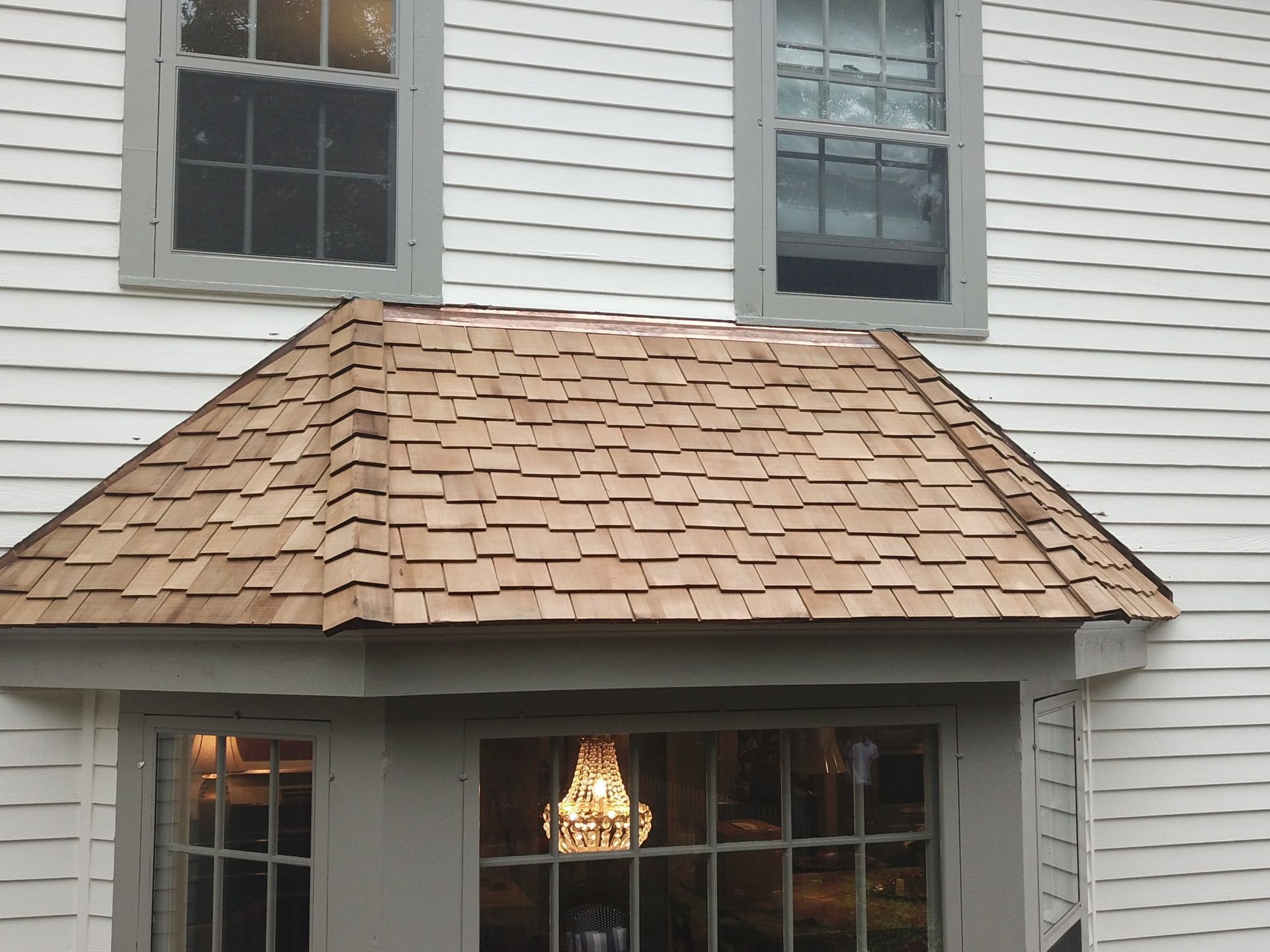 A white house with a wooden roof and a bay window.