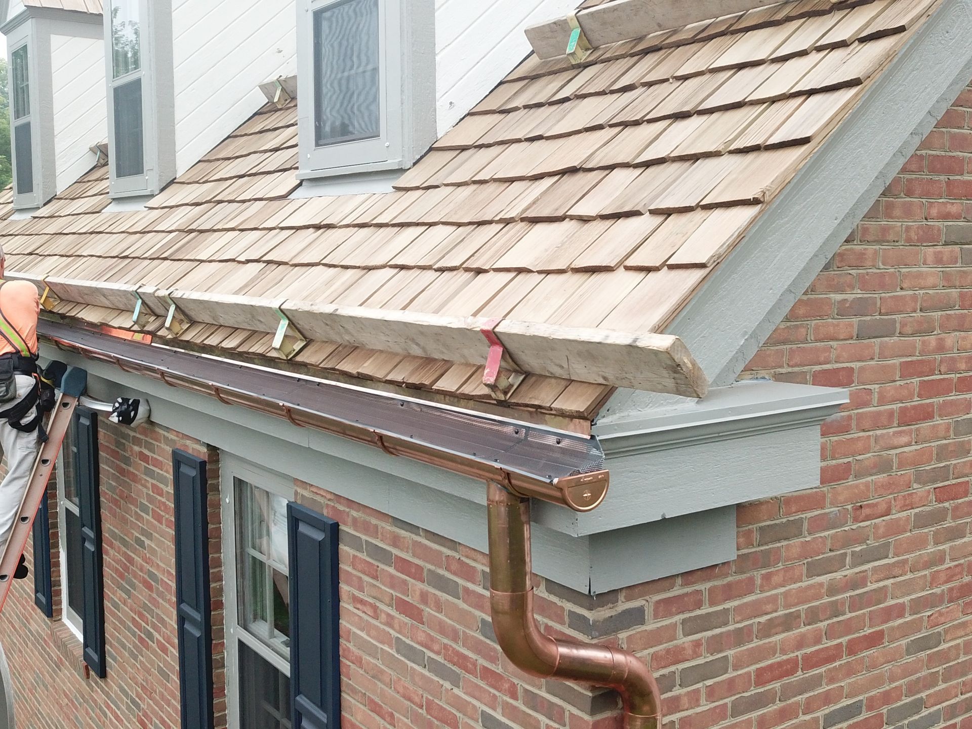 A man is working on the roof of a brick house.