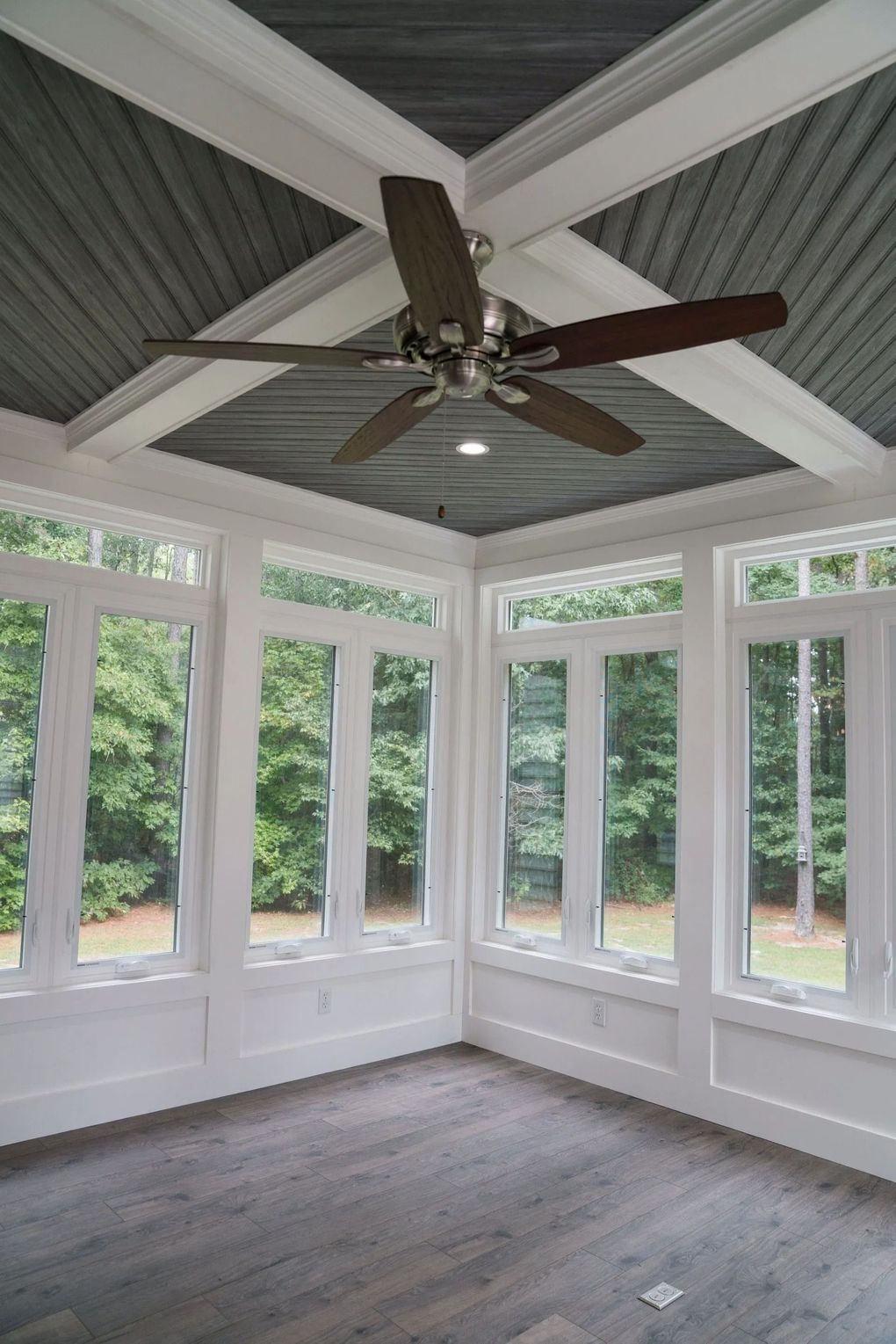 Sunroom with white trim, gray ceiling, large windows, and ceiling fan.