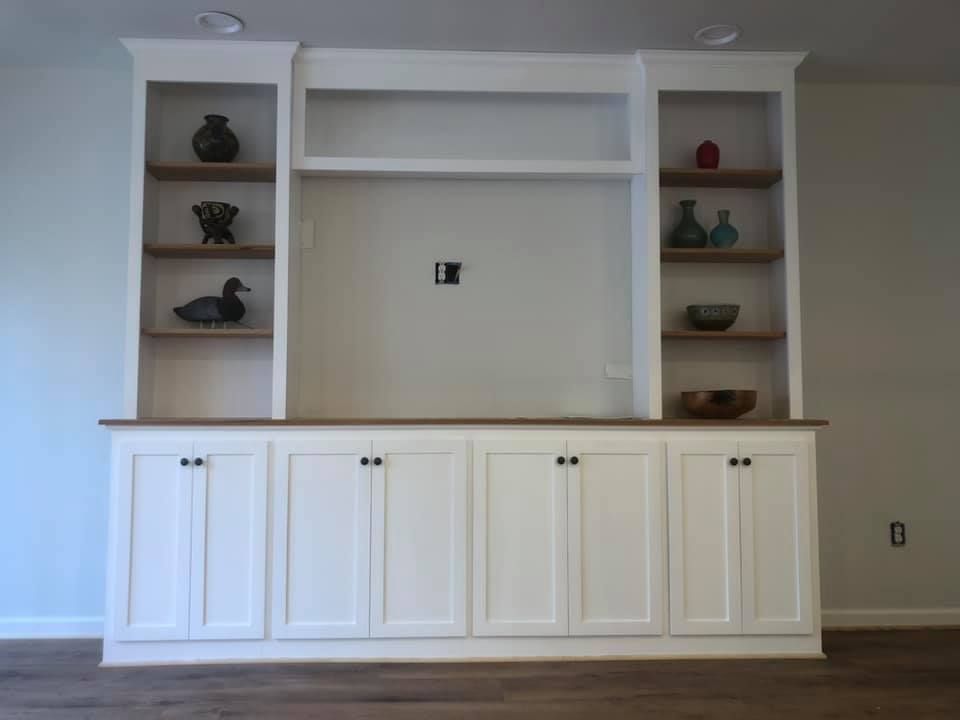 A living room with white cabinets and wooden shelves.