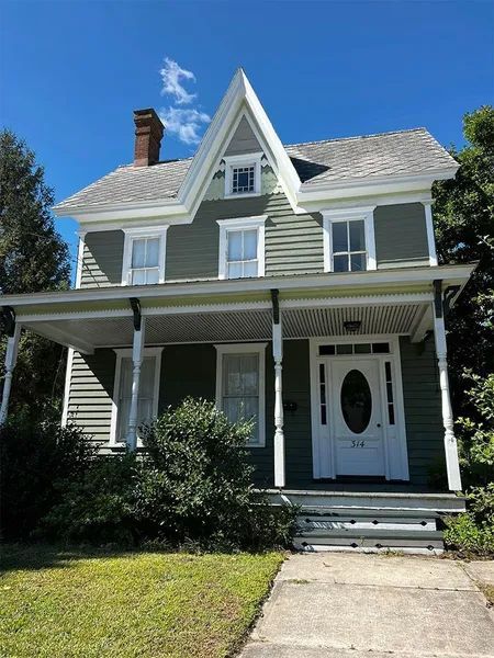 A green house with a white door and porch