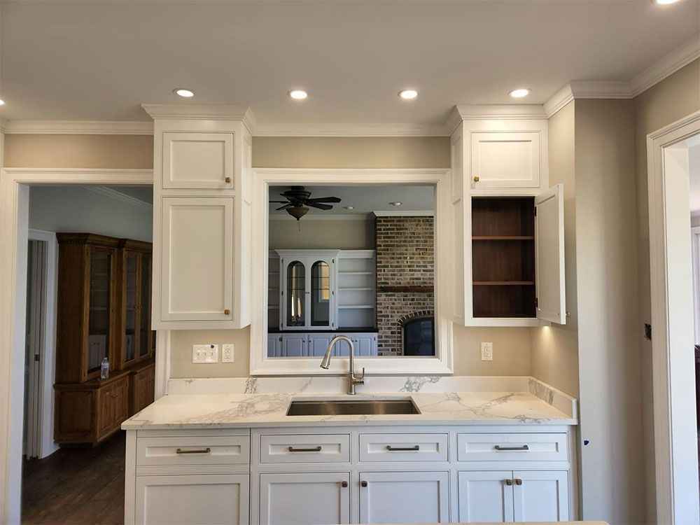 A kitchen with white cabinets, a sink, and a window.