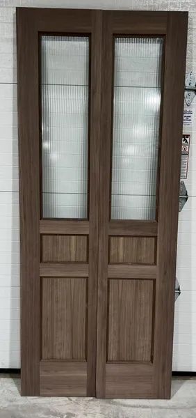 A pair of wooden doors with glass panels are sitting next to a garage door.