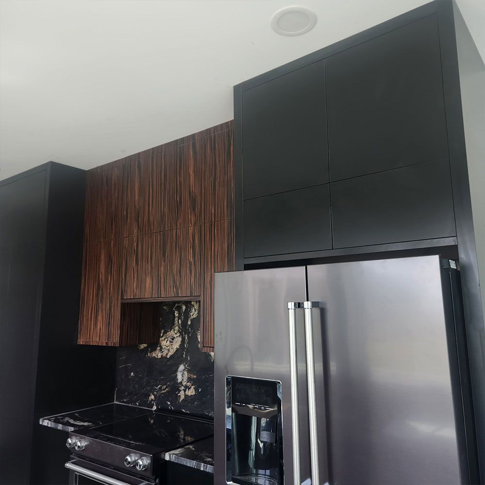A kitchen with black cabinets and a stainless steel refrigerator