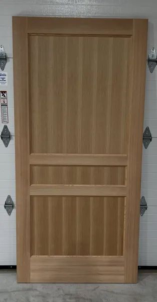 A wooden door is sitting in front of a garage door.