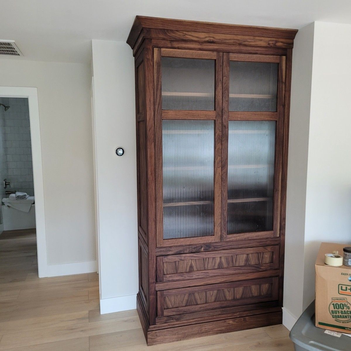 A wooden cabinet with glass doors and drawers in a living room