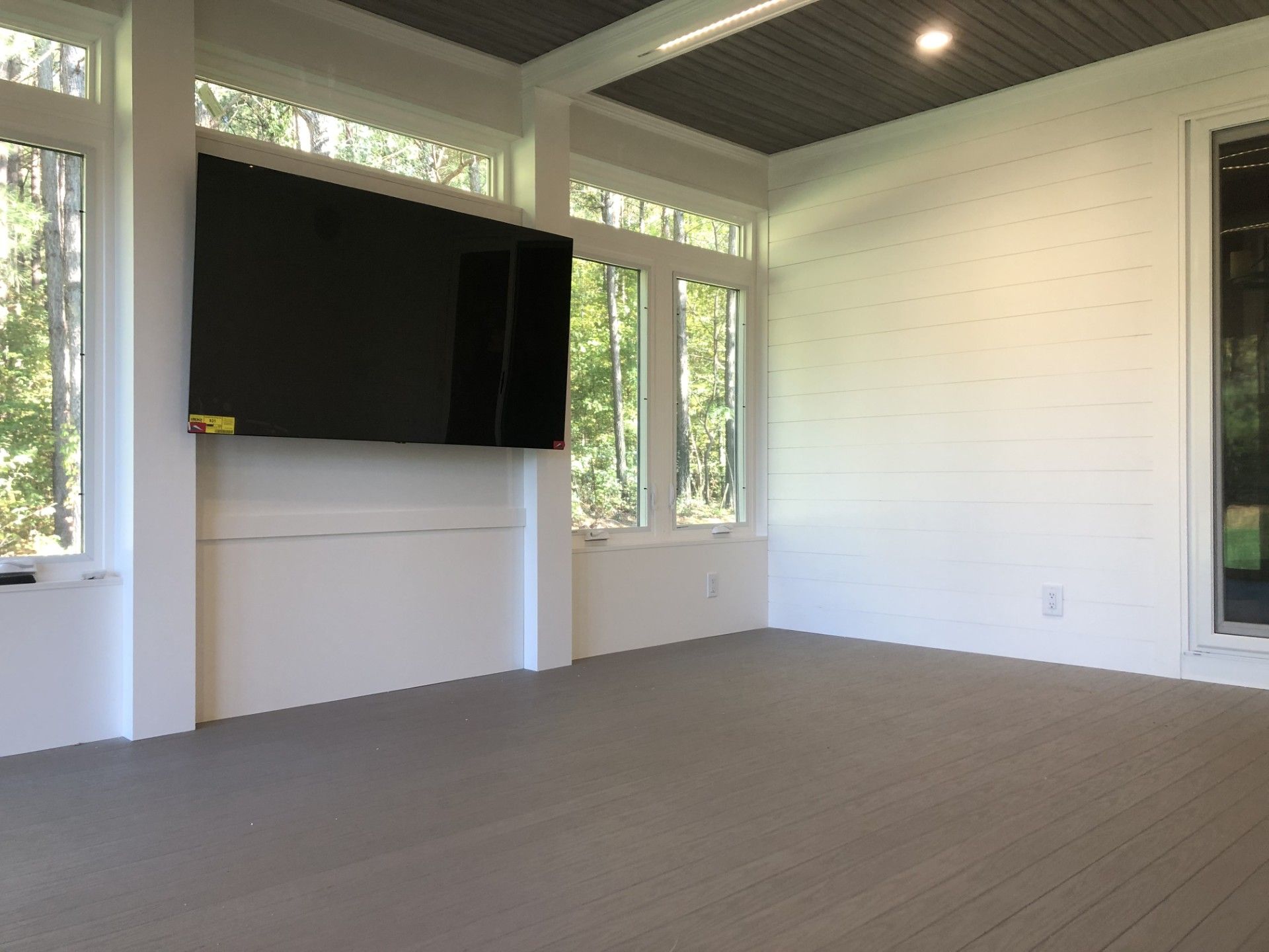 An empty room with a flat screen tv mounted on the wall.