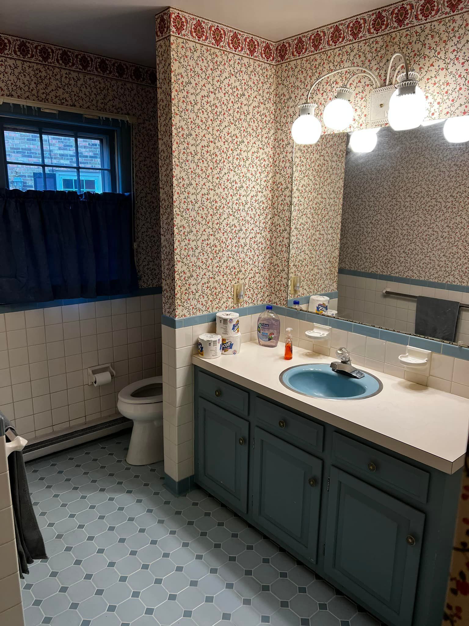 A bathroom with a toilet , sink , and mirror.