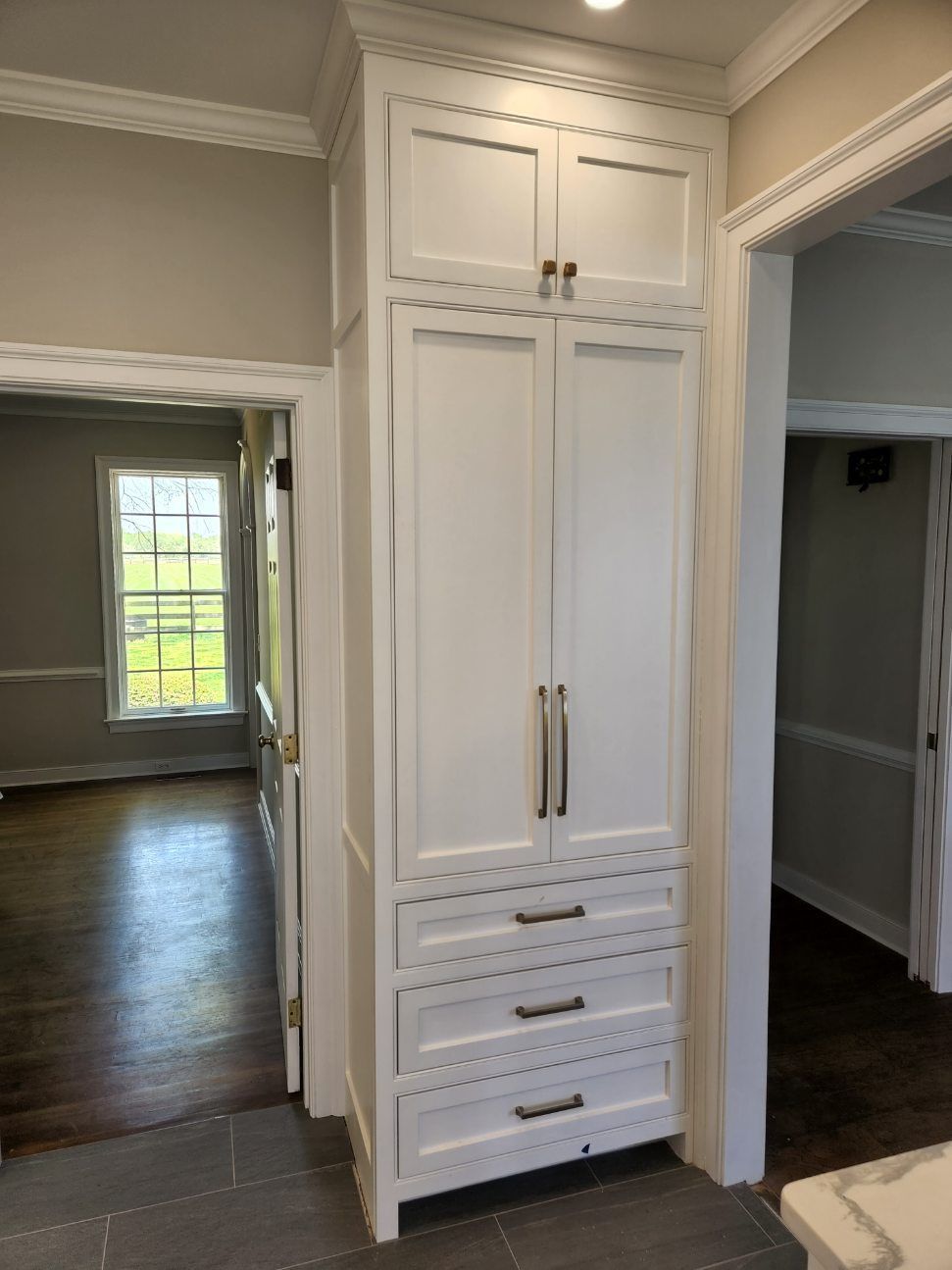 A white cabinet with drawers in a kitchen next to a window.