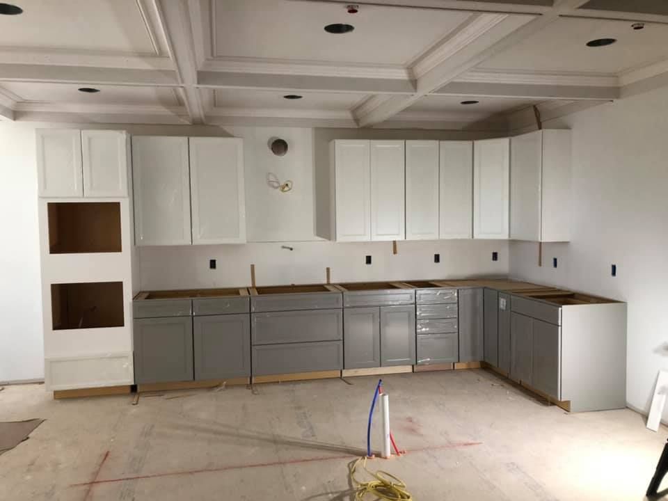A kitchen under construction with white cabinets and a sink
