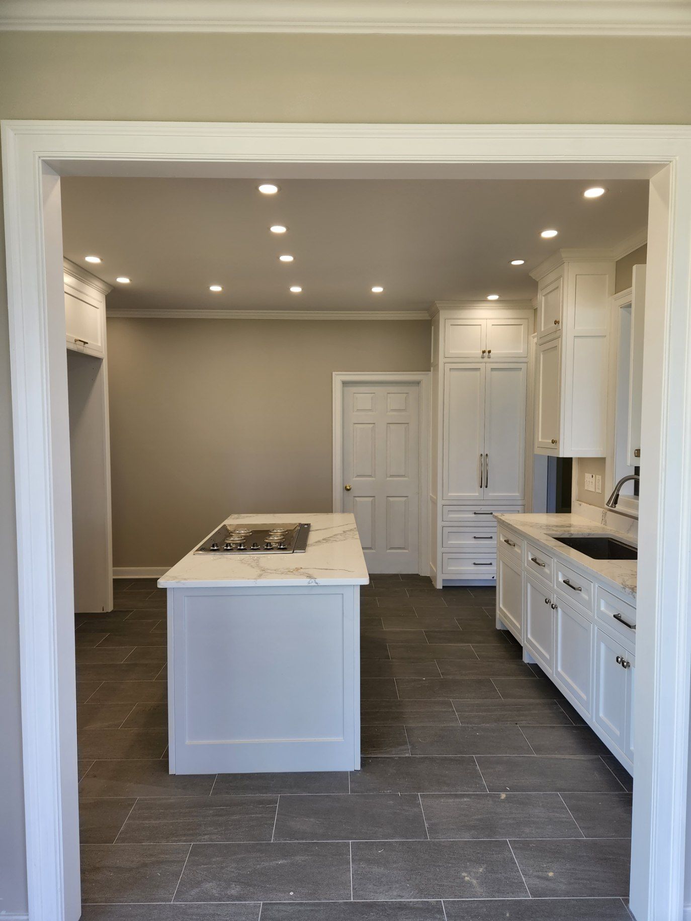 A kitchen with white cabinets and a large island in the middle.