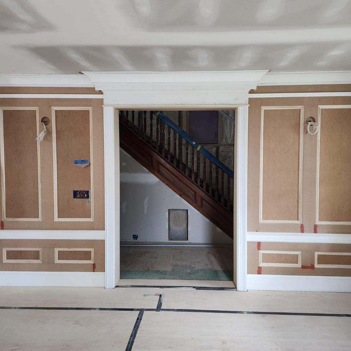 A staircase is visible through a doorway in a room under construction