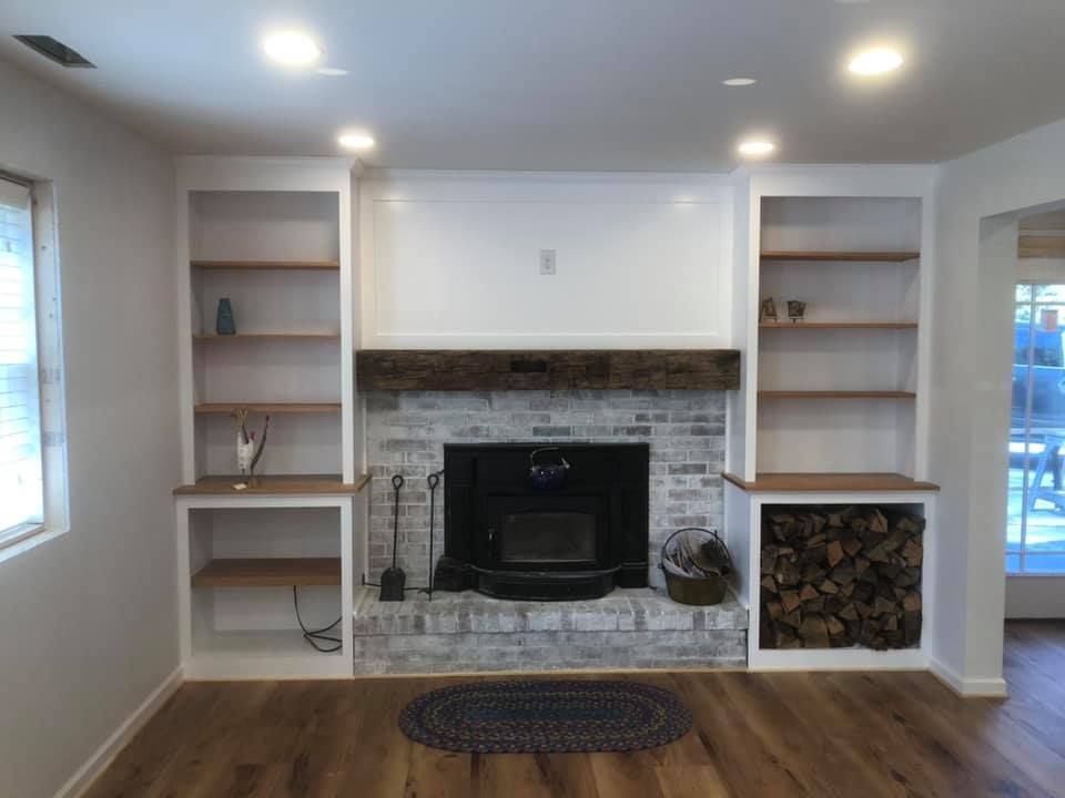 A living room with a fireplace and shelves.
