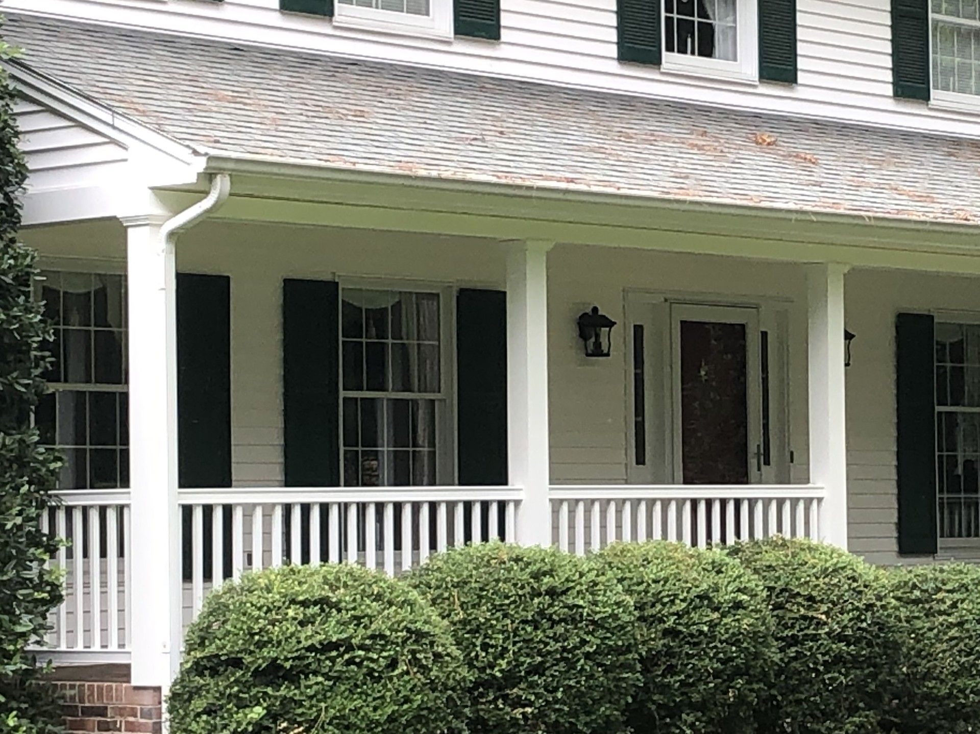 A white house with black shutters and a porch