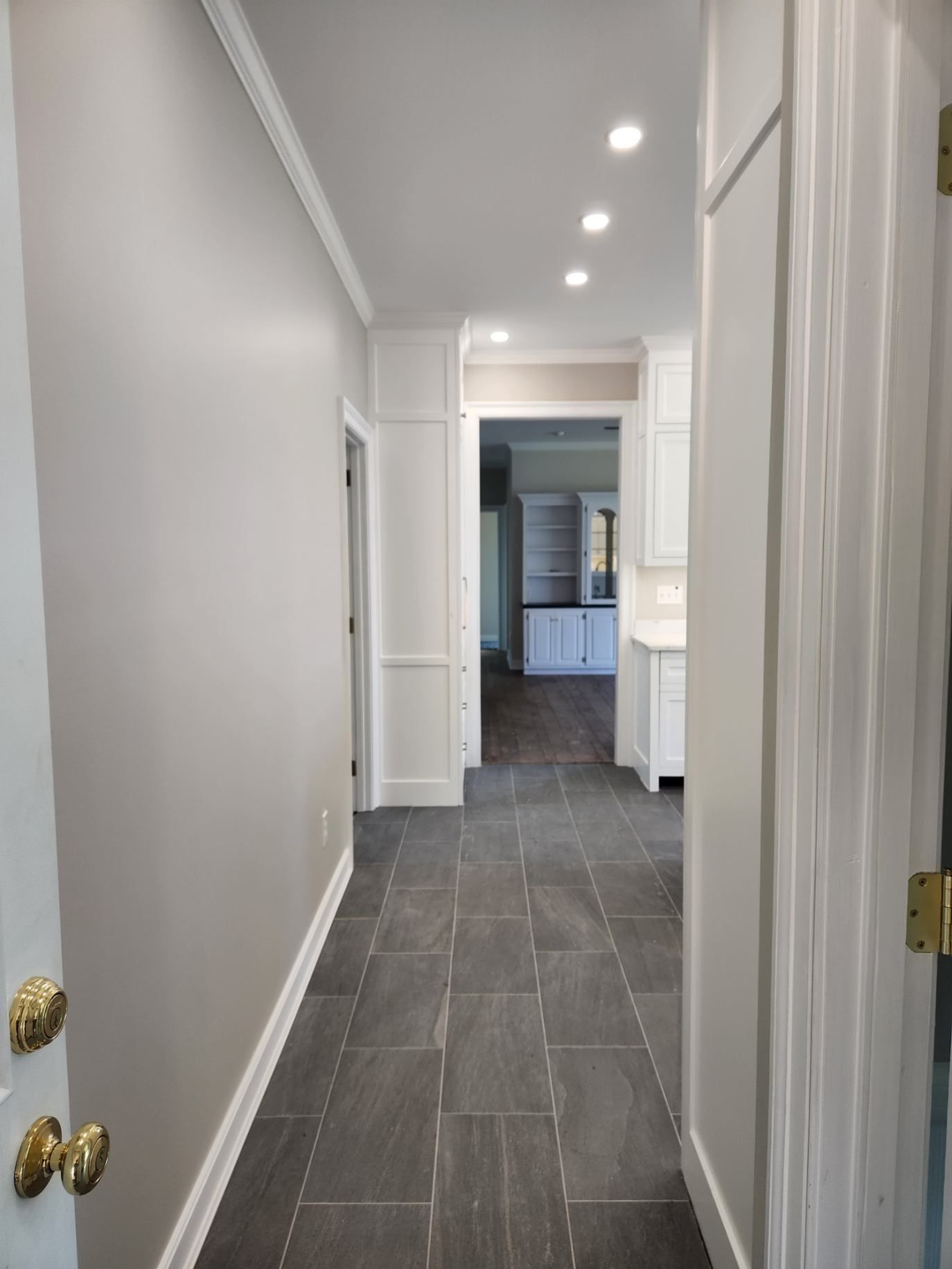 A long hallway leading to a kitchen and a bathroom in a house.