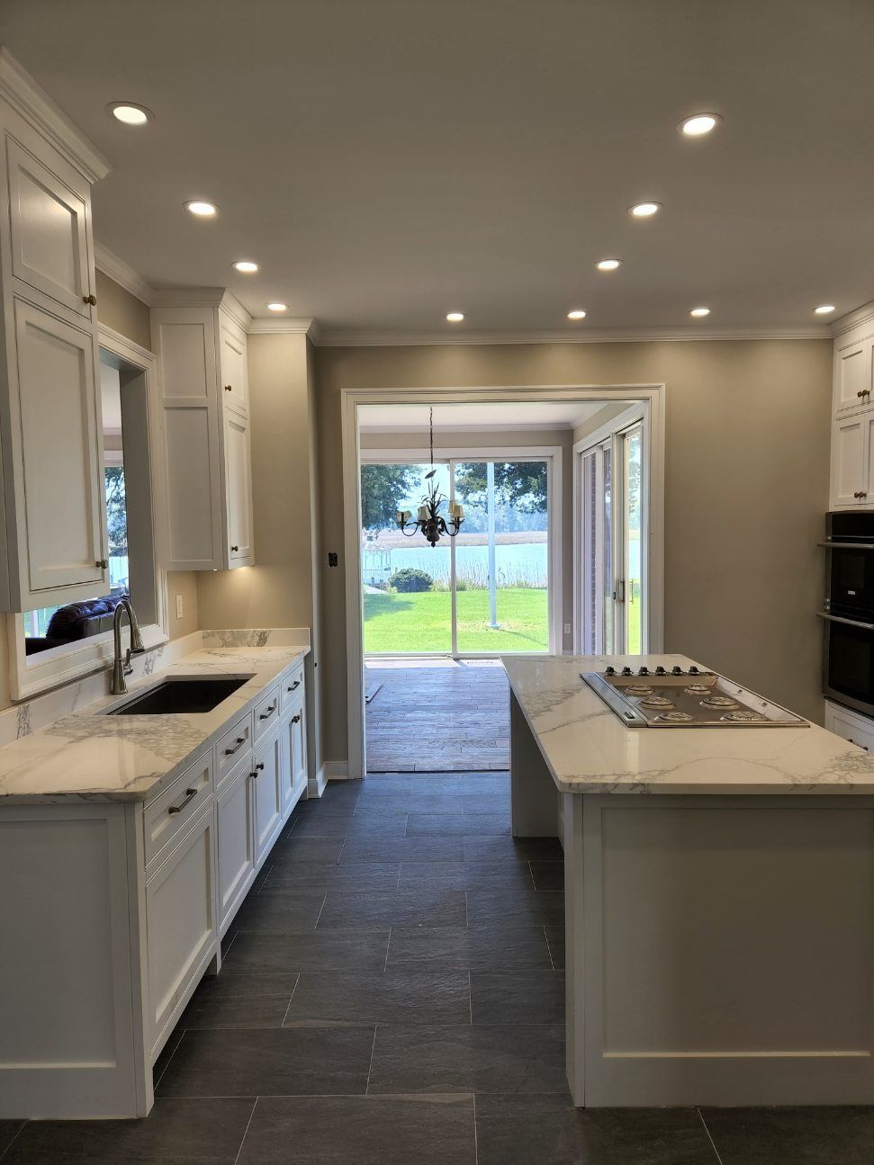 A kitchen with white cabinets, a sink, and a large island.