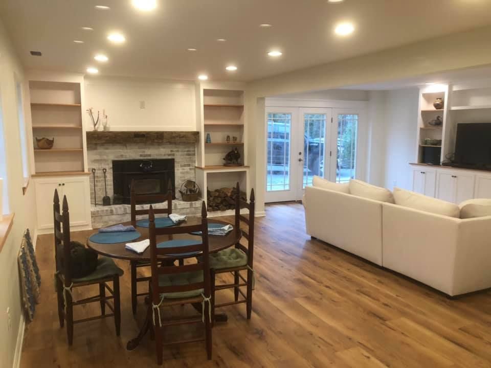 A living room with a dining table and chairs and a fireplace.