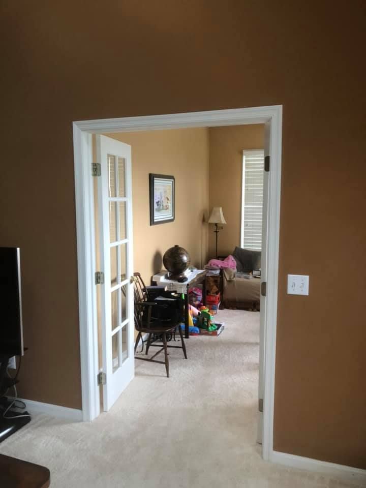 A living room with brown walls and white french doors