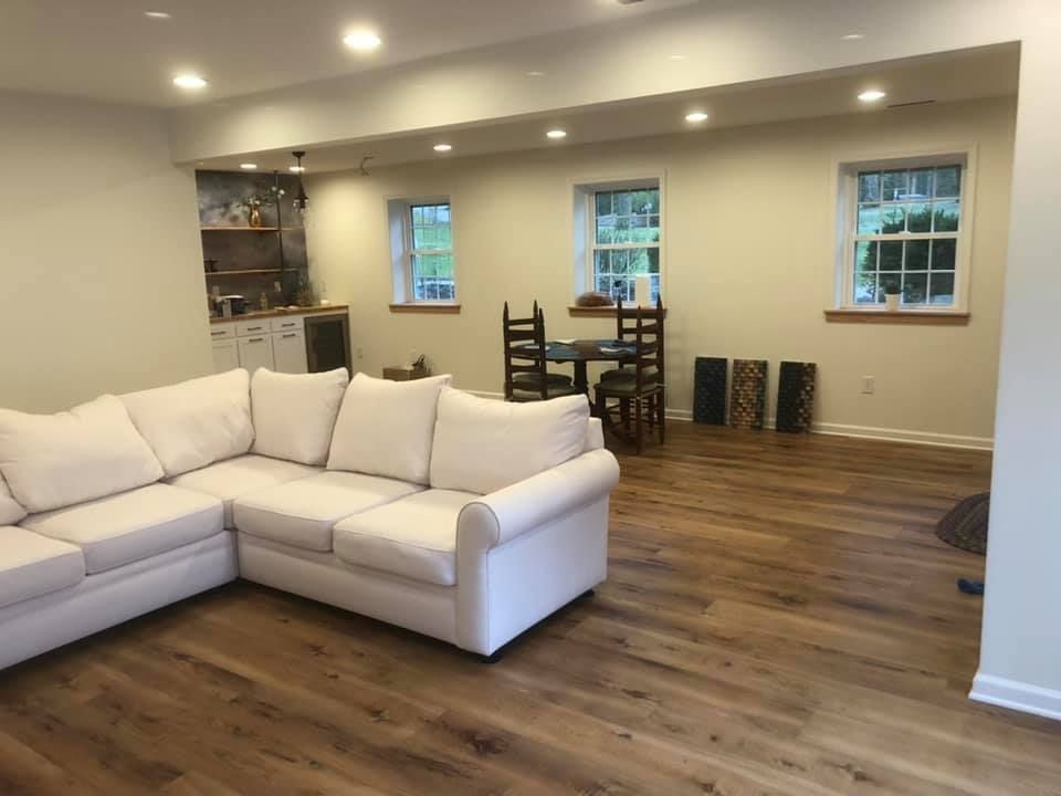 A living room with a white sectional couch and hardwood floors.