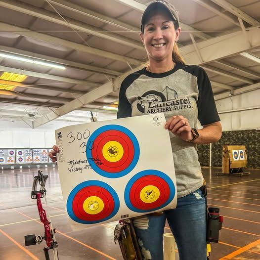 Woman holding archery target with perfect scores.