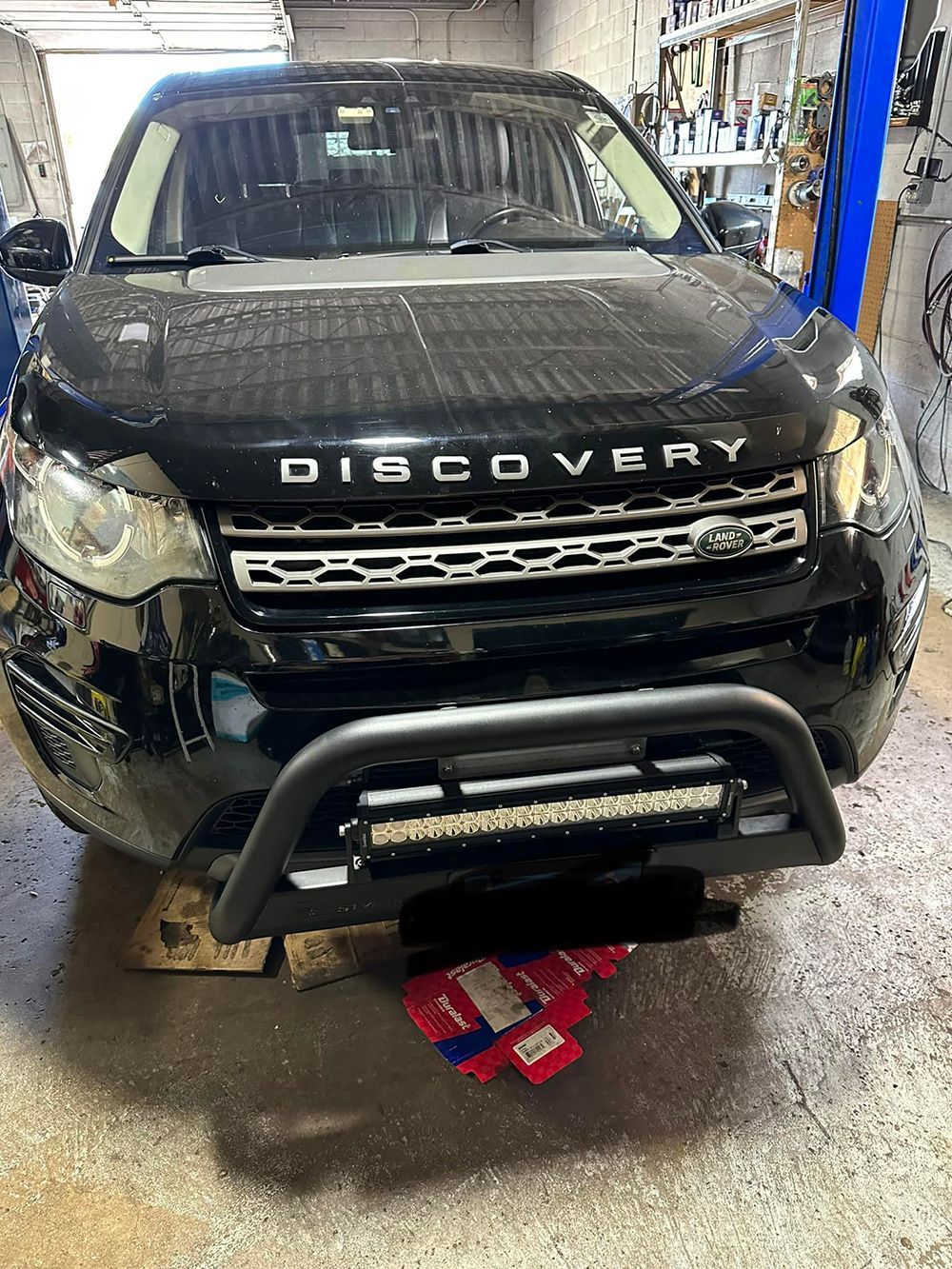 A black land rover discovery is parked on a lift in a garage.