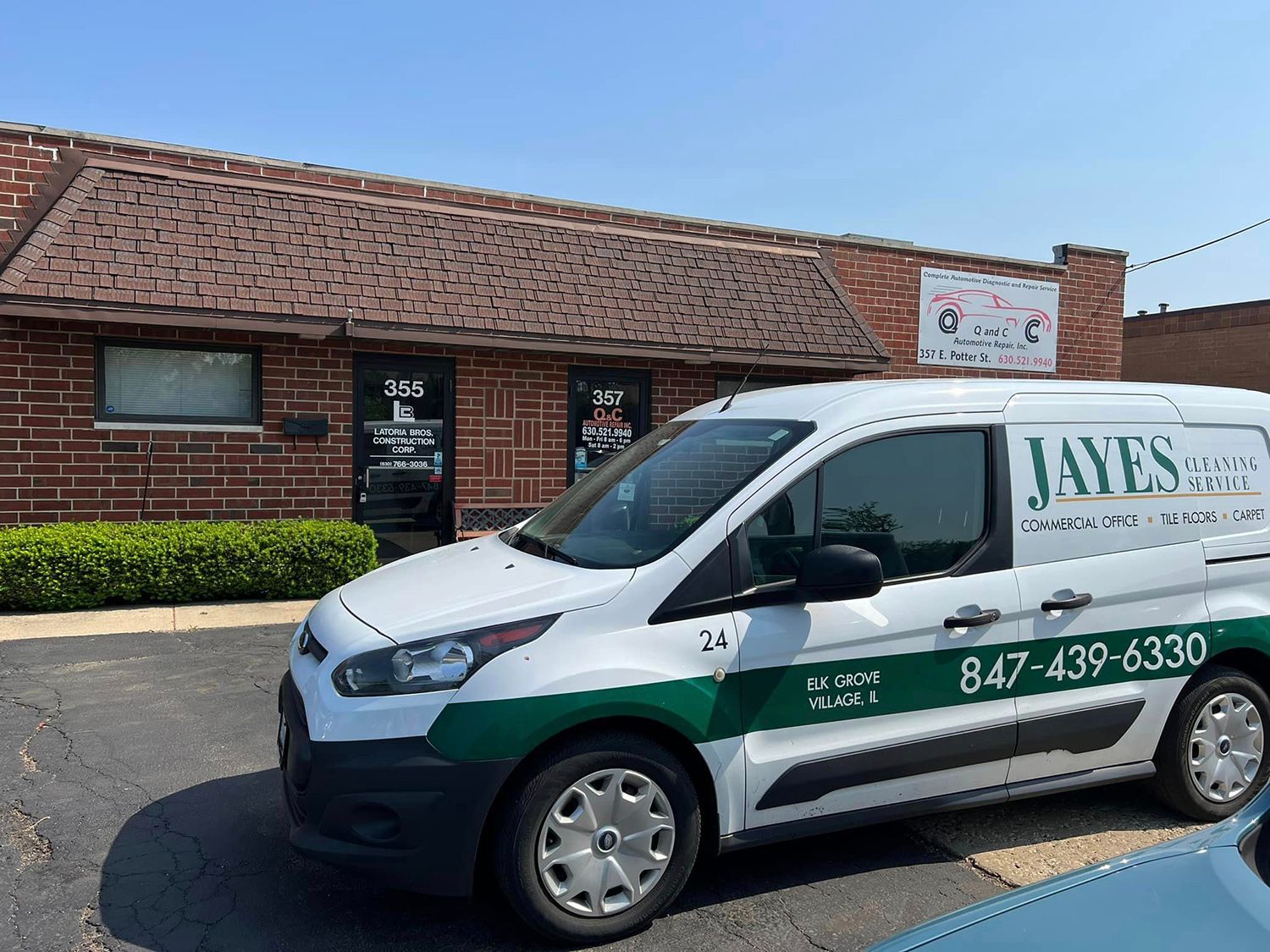 A white van is parked in front of a brick building.