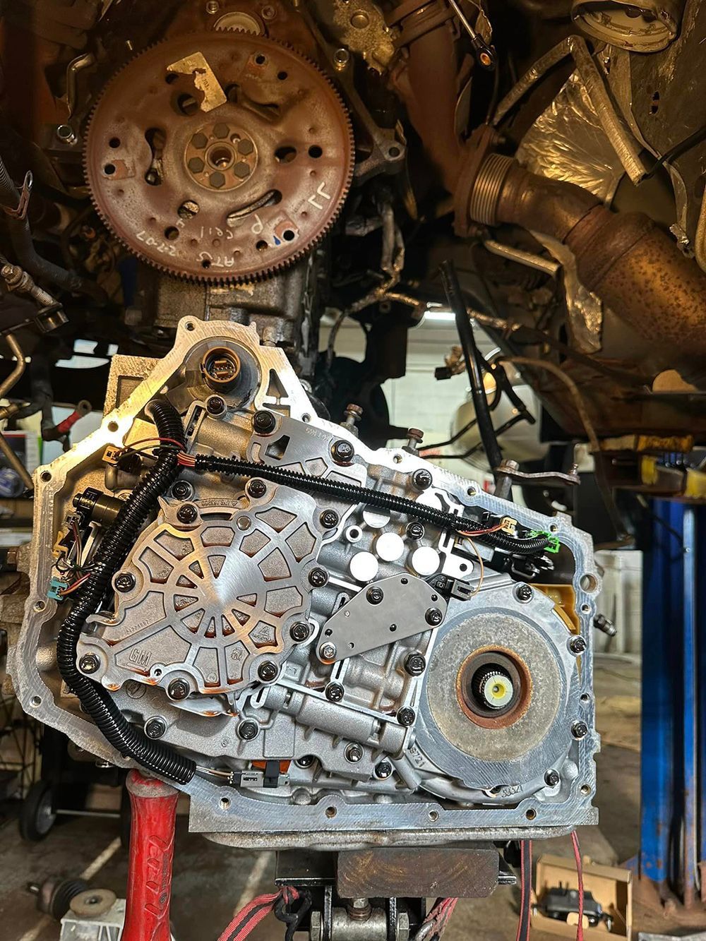 A car engine is sitting on a lift in a garage.