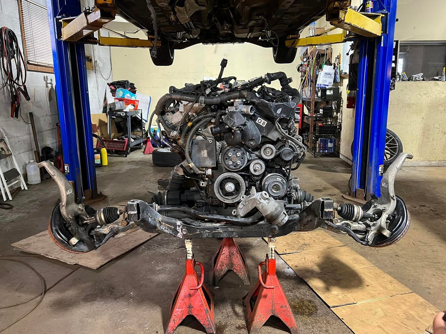 A car engine is sitting on a jack in a garage.