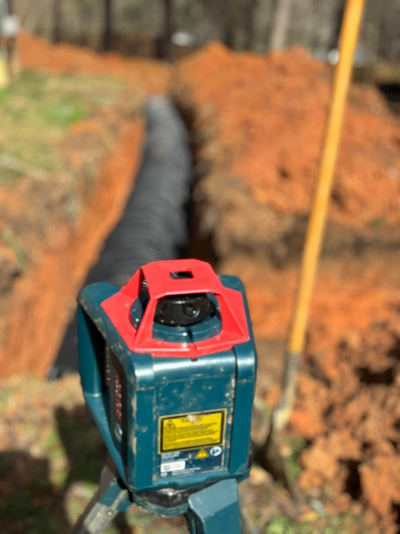 Surveying tool on tripod beside a trench in a dirt construction site