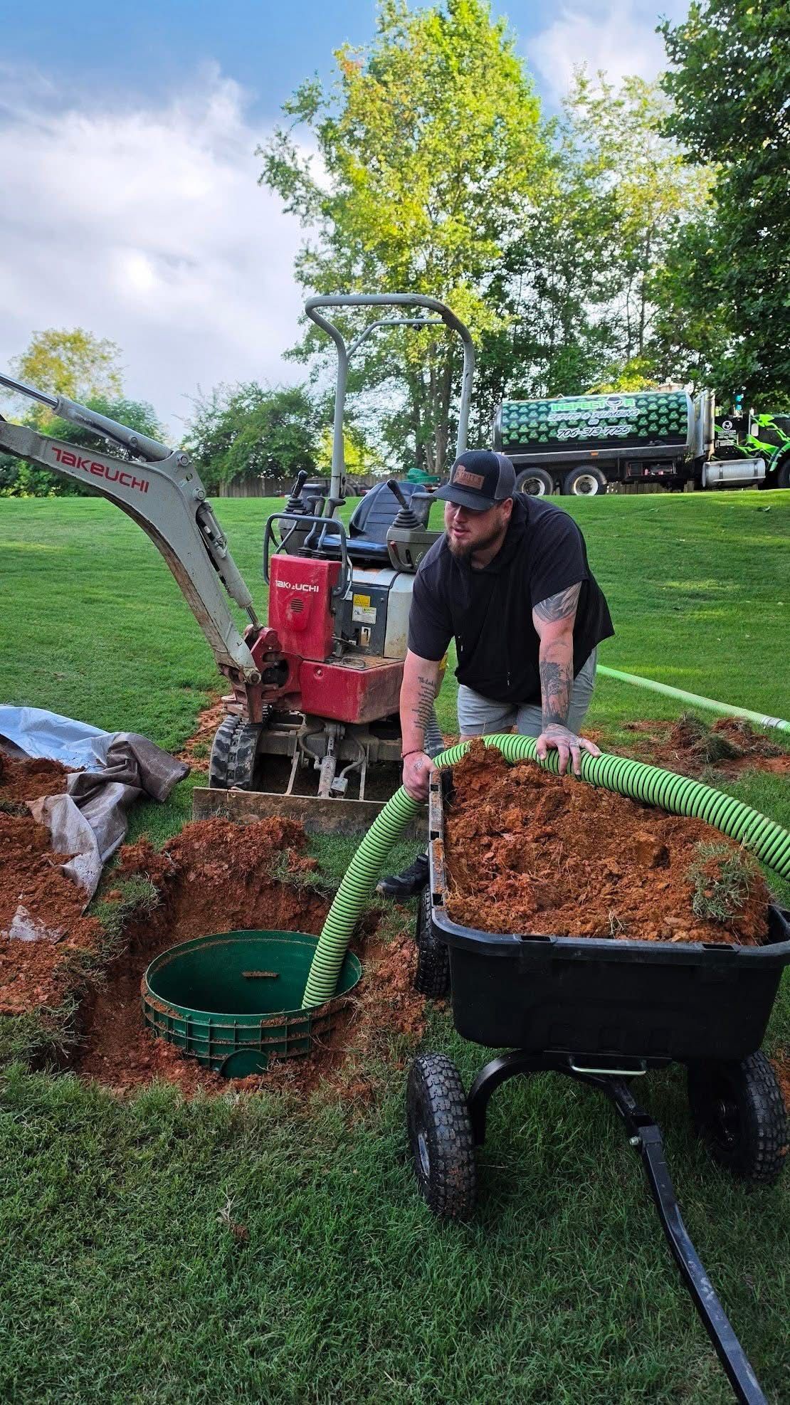 Worker feeding wood chips into a green stump grinder in a grassy yard