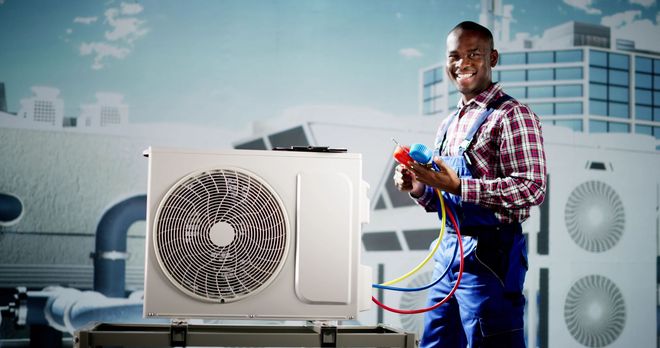 Man in plaid shirt cleaning an AC unit with a screwdriver, white wall setting.