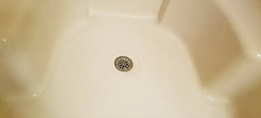 A white bathtub with a drain in the middle of it.