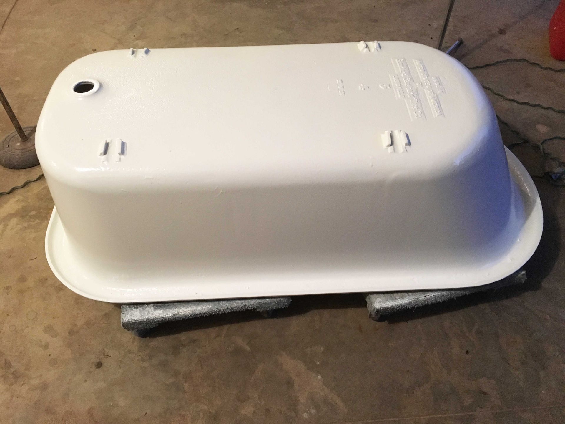 A white bathtub is sitting on a concrete floor.