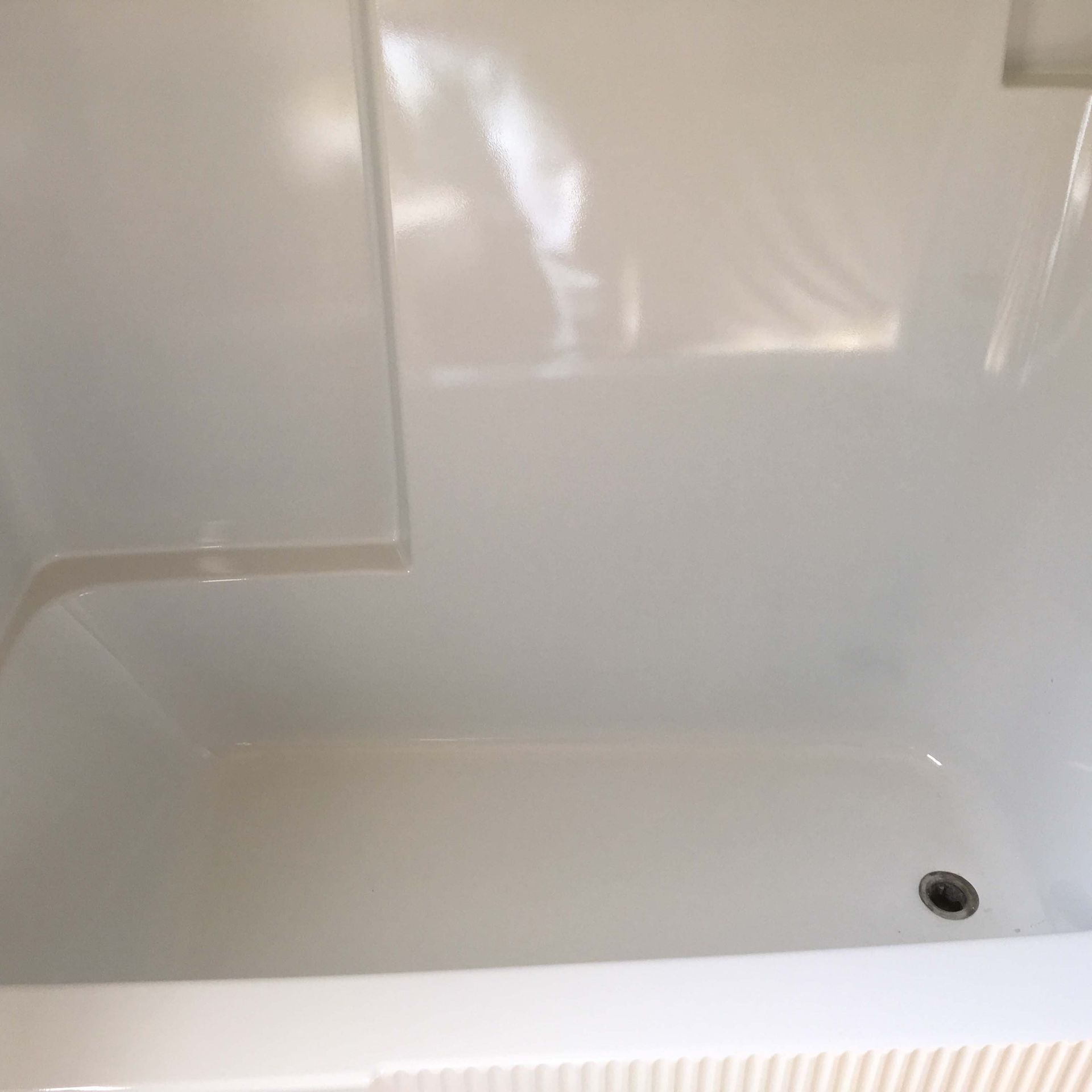 A white bathtub in a bathroom with a drain.