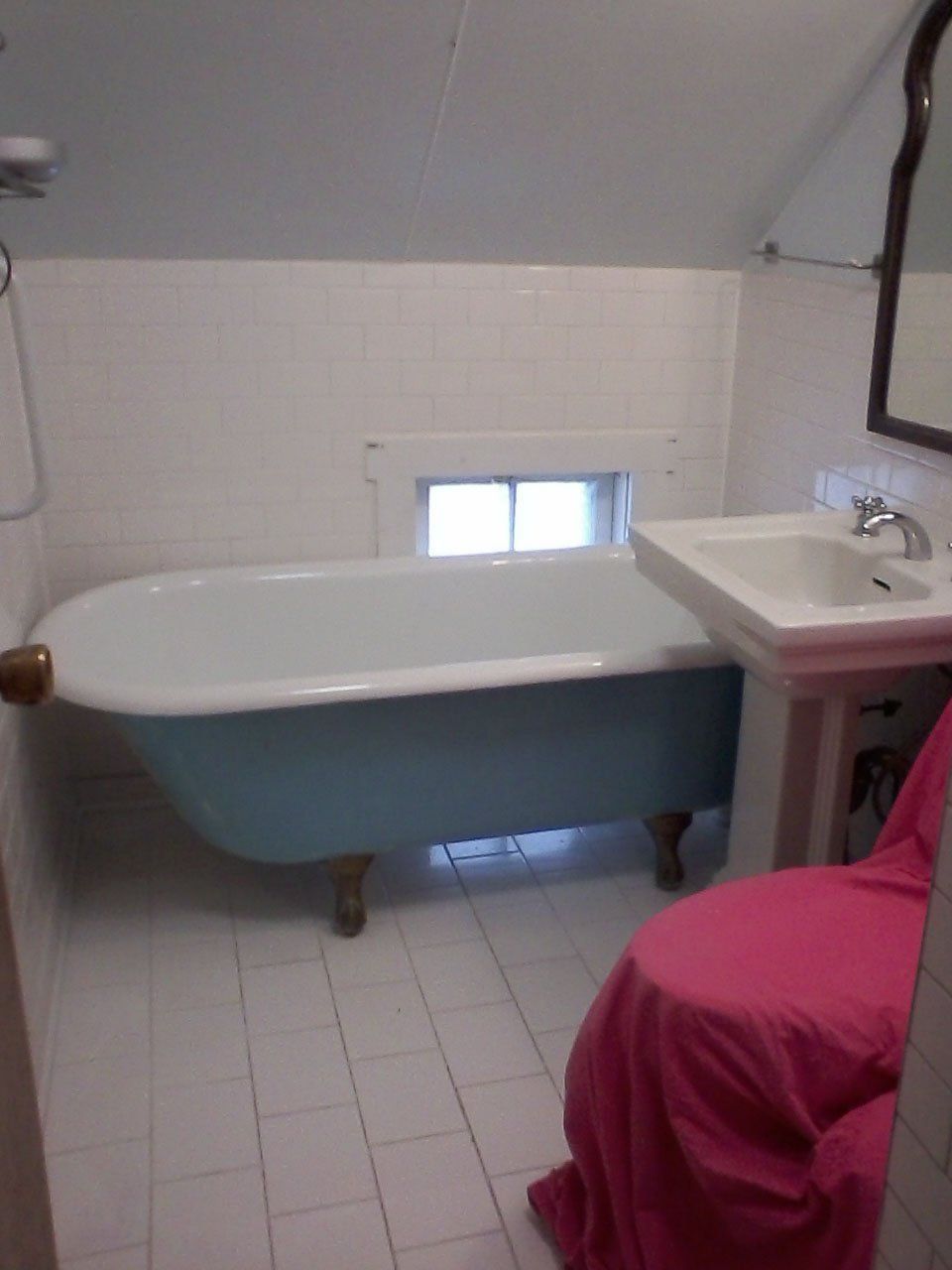 A bathroom with a blue tub and a pink chair