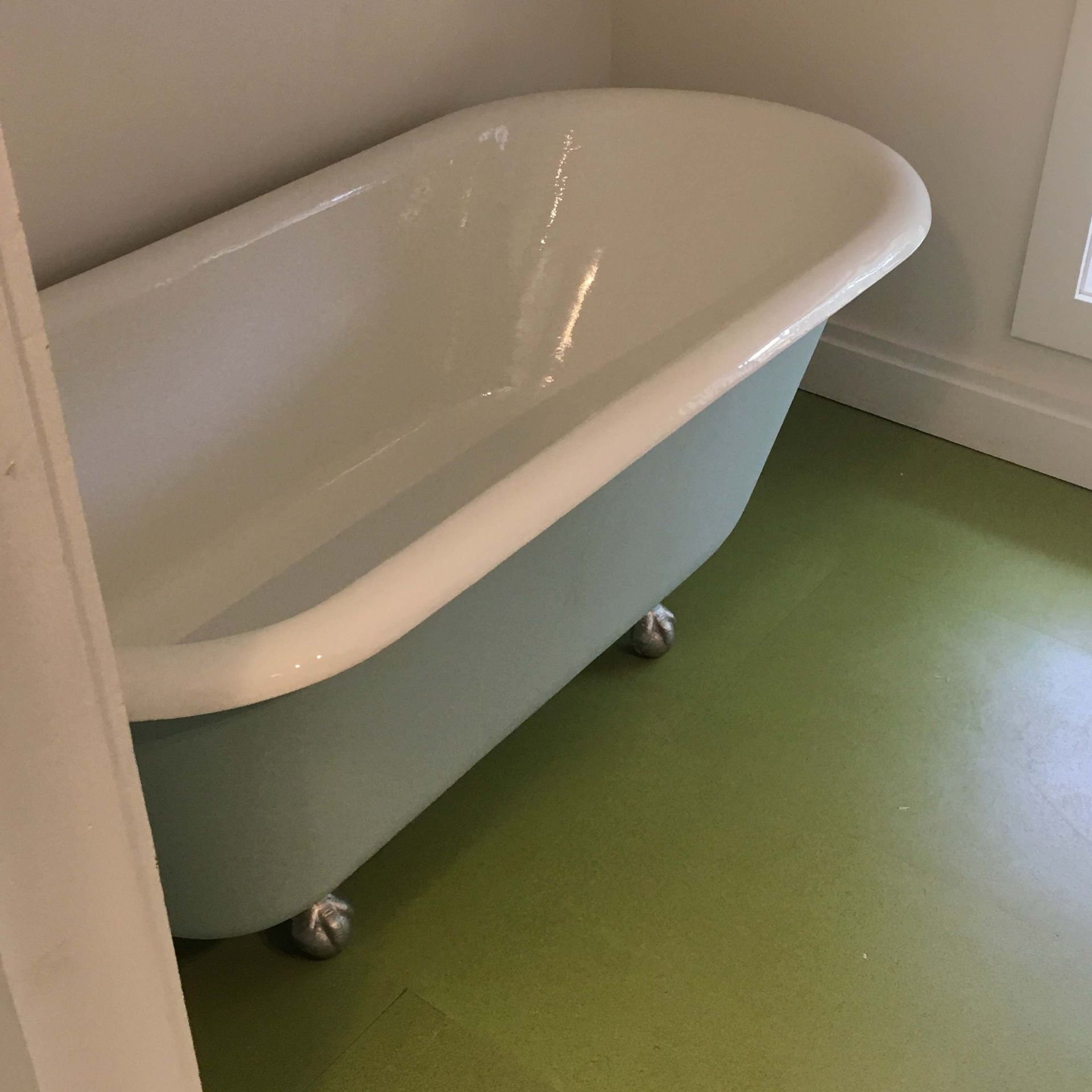 A bathtub is sitting on a green floor in a bathroom