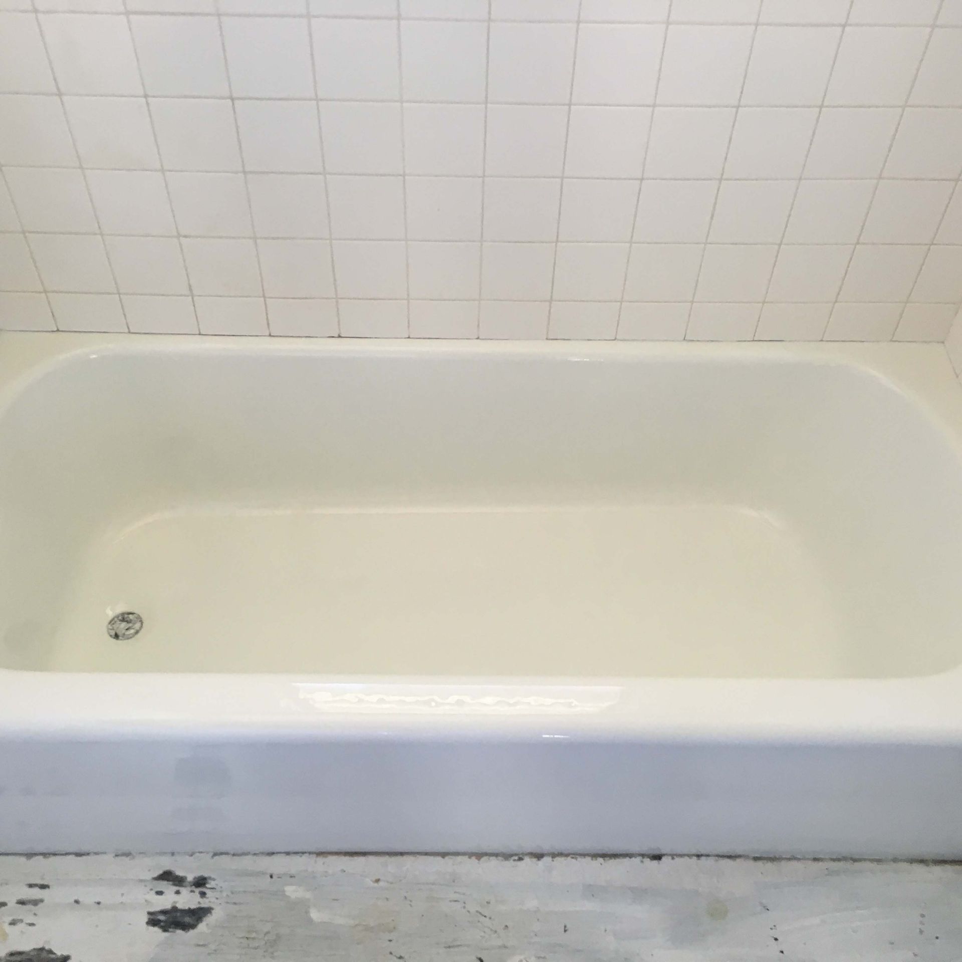 A white bathtub is sitting in a bathroom next to a tiled wall.
