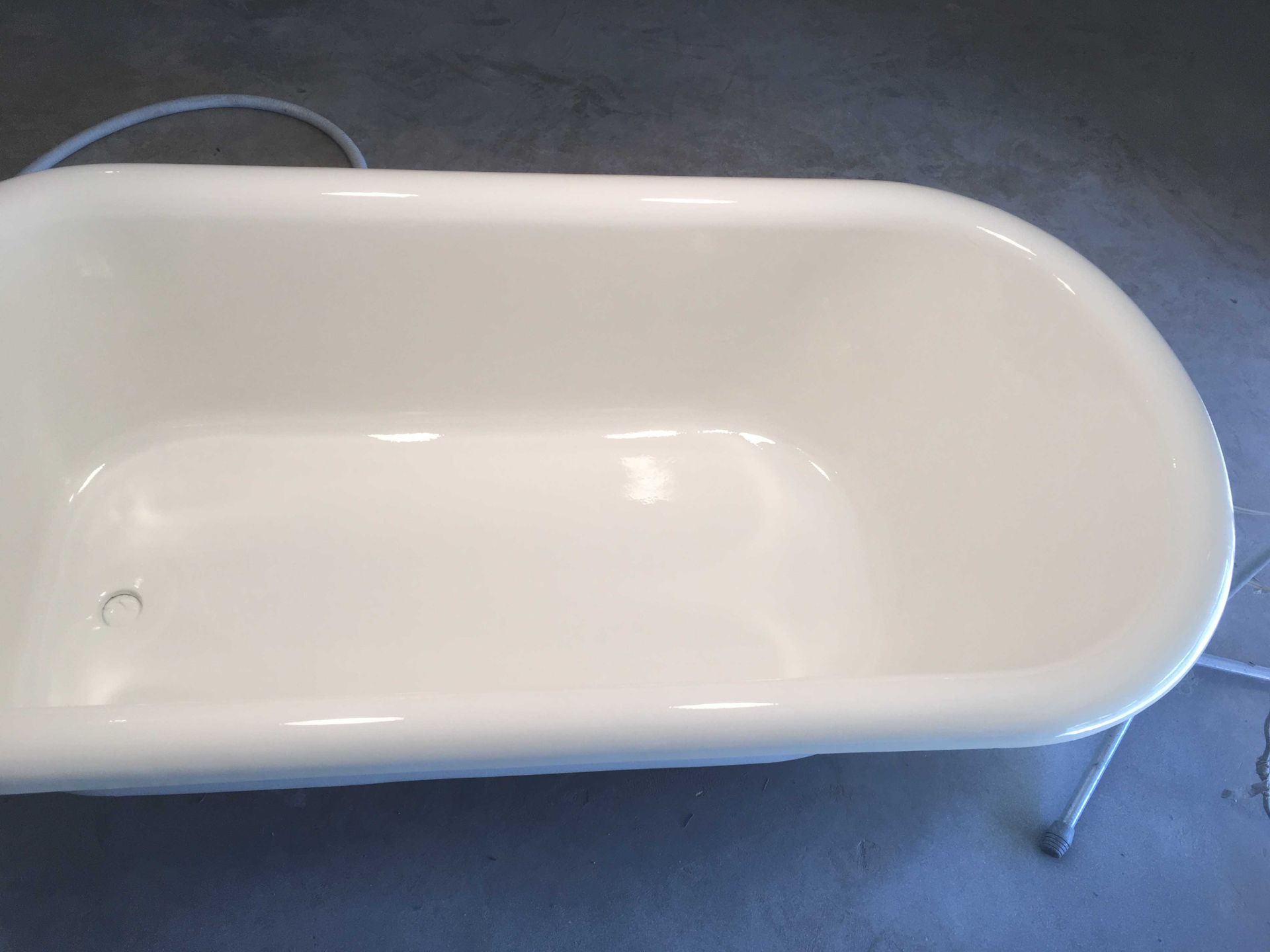 A white bathtub is sitting on a concrete floor