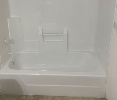 A white bathtub with a shower stall attached to it in a bathroom.