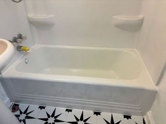 A bathtub in a bathroom with a black and white tile floor.