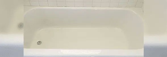 A white bathtub in a bathroom with white tiles.