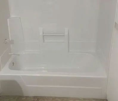 A white bathtub with a shower stall attached to it in a bathroom.