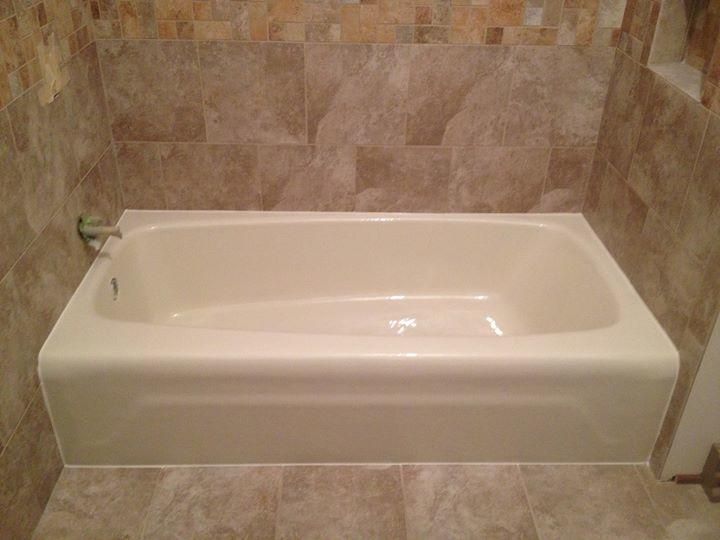 A white bathtub is sitting in a bathroom next to a tiled wall.