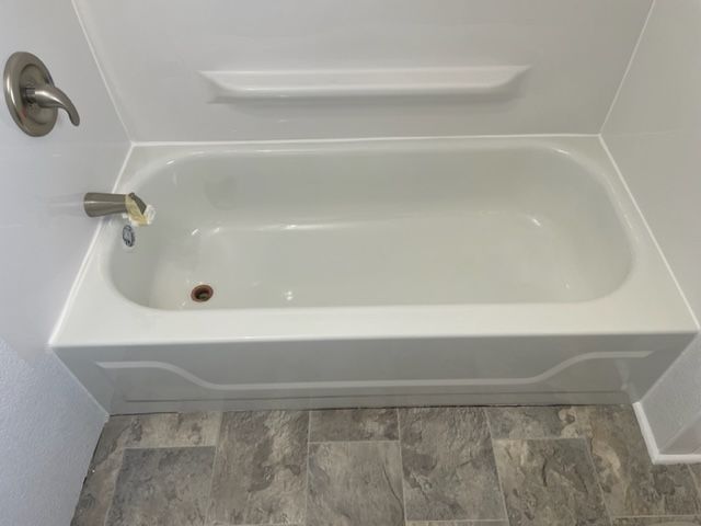 A white bathtub is sitting on a tiled floor in a bathroom.